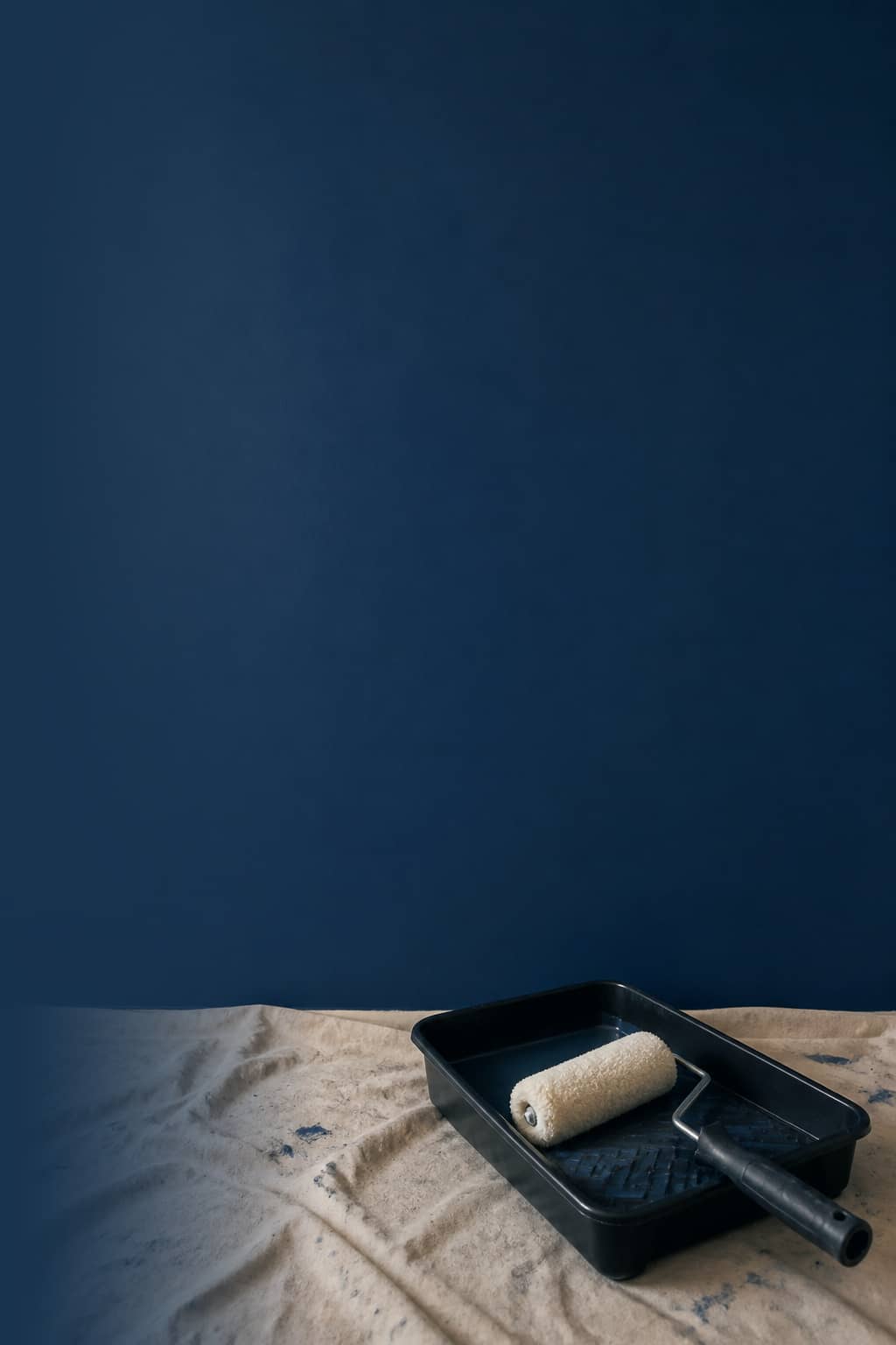 Paint roller against a deep navy painted wall